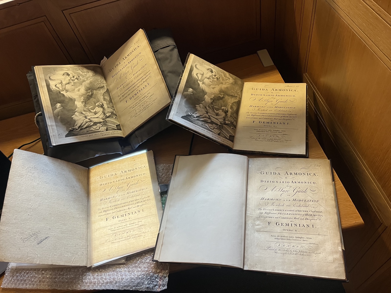 Four copies of the Guida Armonica open on a library table